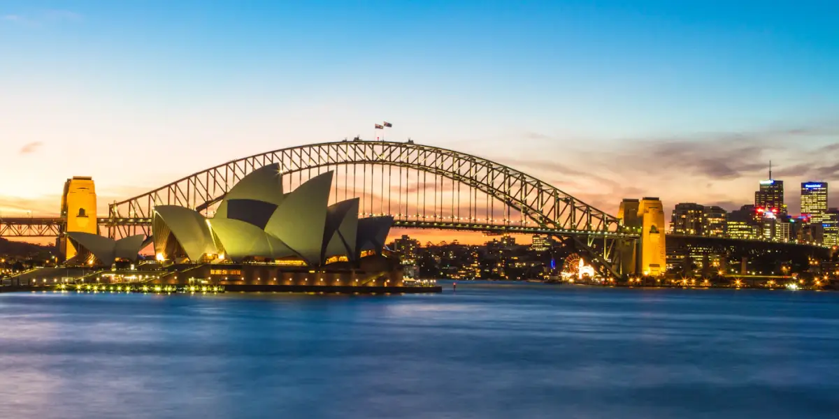 The Sydney Opera House and Sydney Harbour Bridge lit up at dusk, seen across the harbour from Mrs Macquarie's Chair