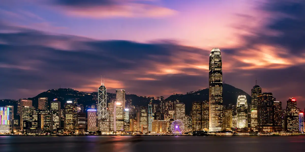Hong Kong Island's skyline at dusk seen across Victoria Harbour from the Kowloon side, with the IFC tower, the Bank of China Tower, the harbourside observation wheel and the Peak behind