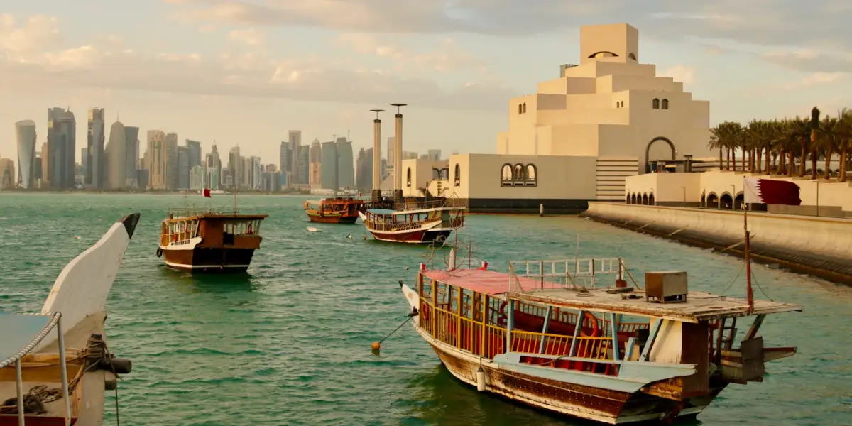 Wooden dhows moored in Doha Bay beside the Museum of Islamic Art, with the West Bay skyline across the water