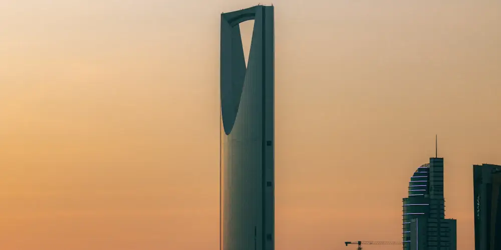 The Kingdom Centre tower with its open, bridged top against a hazy orange sky in Riyadh
