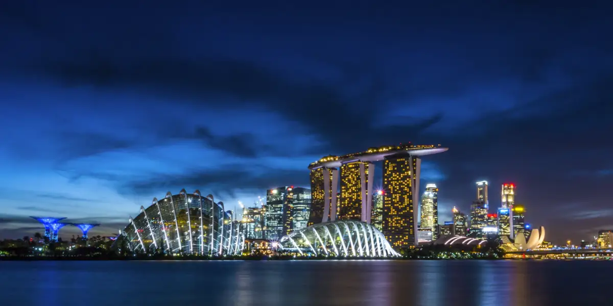 Marina Bay Sands, the Gardens by the Bay conservatory domes and Supertrees, and the city skyline lit up at dusk across Marina Bay