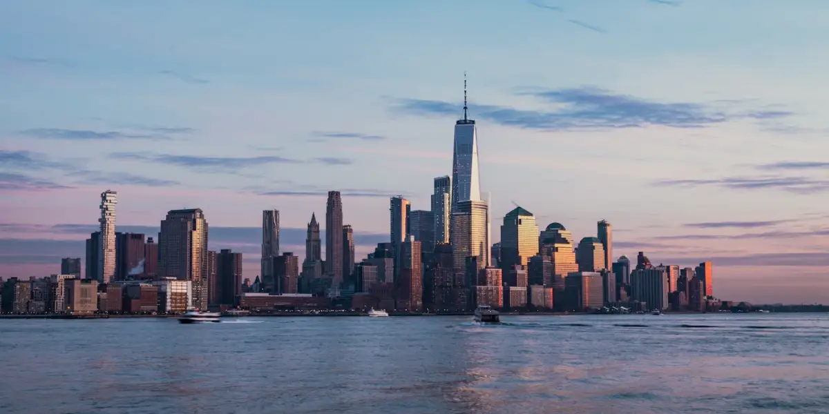 Lower Manhattan's skyline and One World Trade Center at dusk, seen across the Hudson River from Hoboken